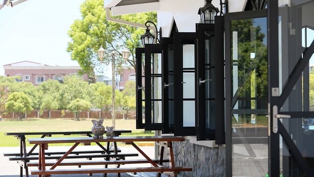 Une terrasse extérieure avec des tables de pique-nique et une statue de hibou décorative.