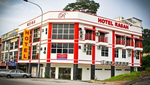 A multi-story hotel with a prominent red and white facade, large windows, and balconies.