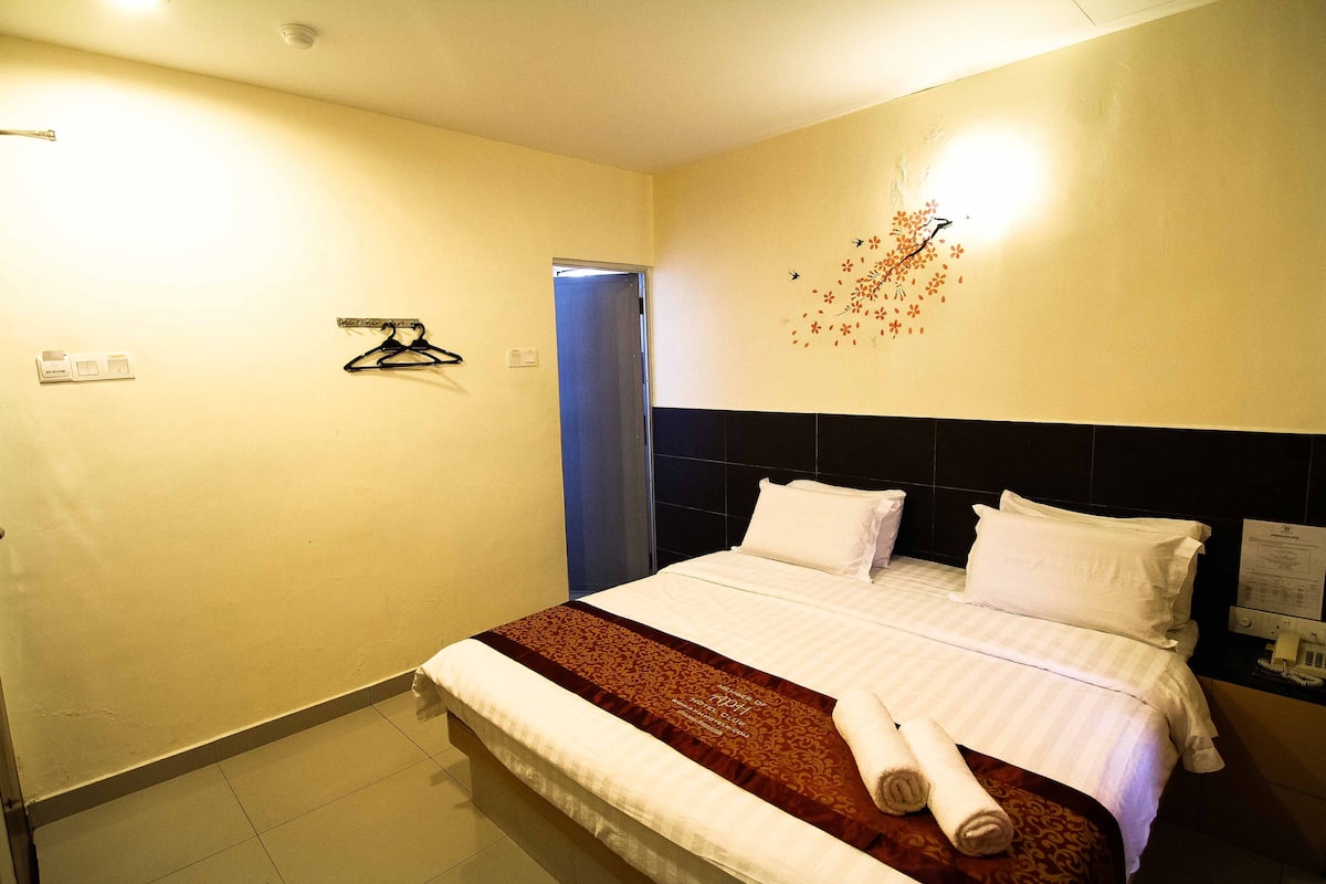 A hotel room with a bed, a wall-mounted towel rack, and a door.