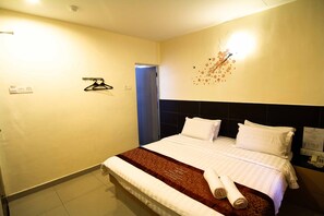 Une chambre d’hôtel avec un lit, un porte-serviettes fixé au mur et une porte.