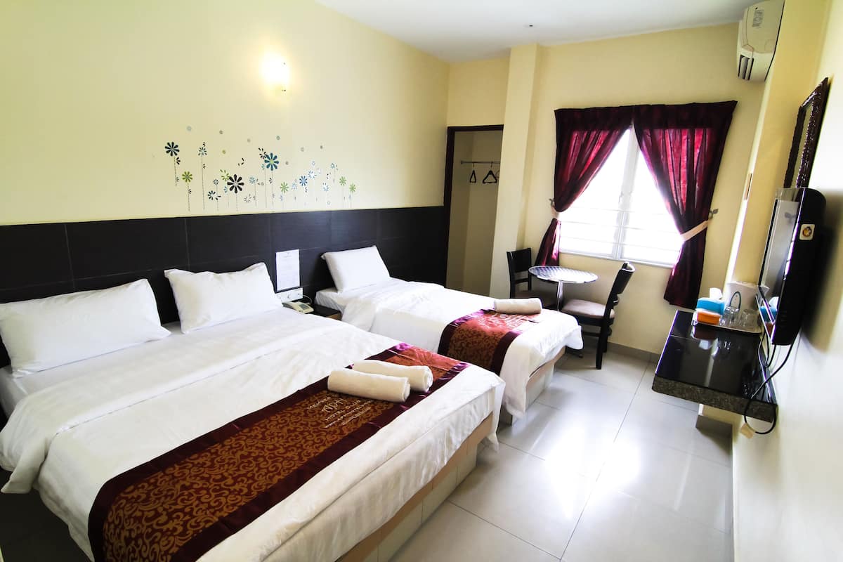 A hotel room with two beds, a desk, a chair, a TV, and a window with curtains.