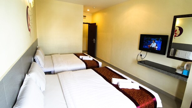 A hotel room with two beds, a television, a mirror, and a shelf with toiletries.