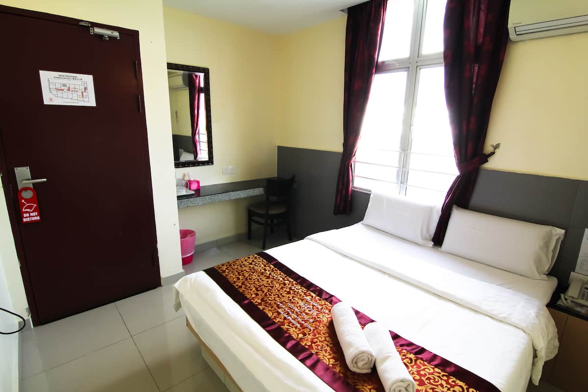 A hotel room with a bed, a desk, a chair, a mirror, and a window with curtains.