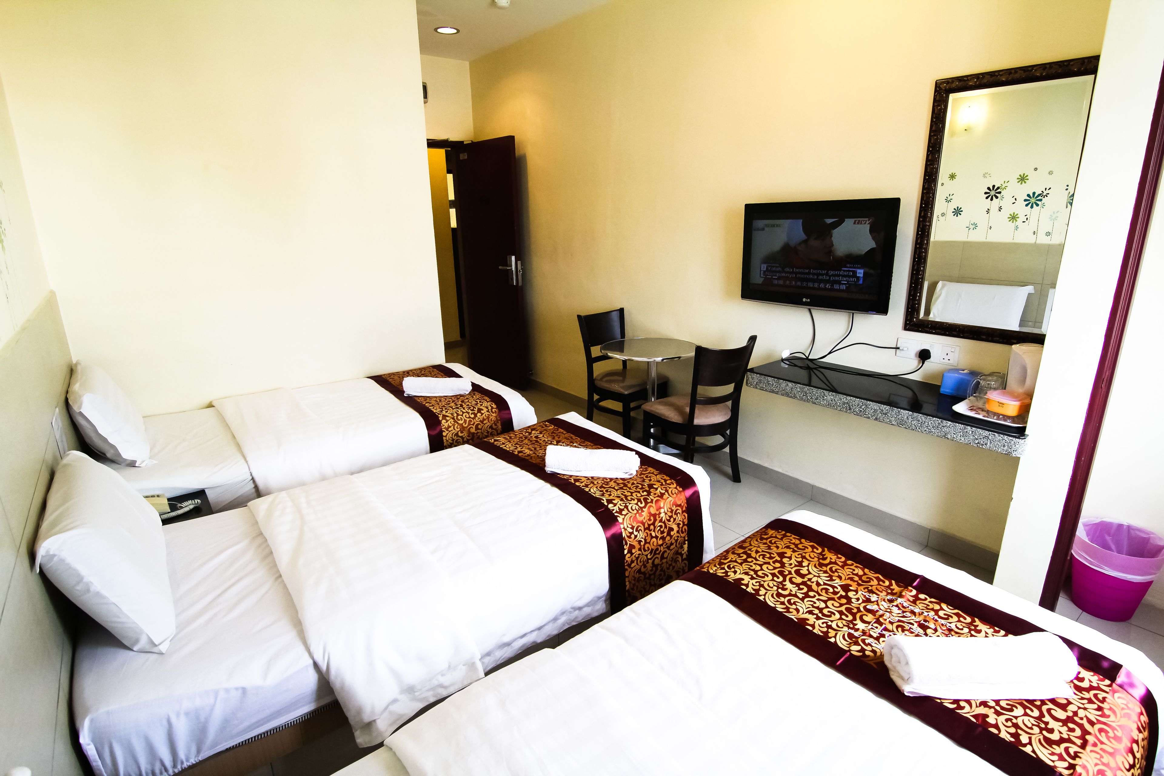 A hotel room with two beds, a desk, a chair, a television, and a bathroom.