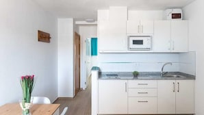 Una cocina moderna con armarios blancos, un microondas y un lavamanos.