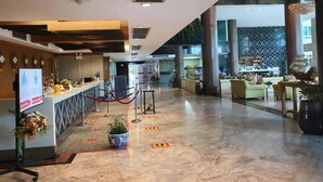 Un vestíbulo amplio con mostrador de recepción, zona de estar y bar.