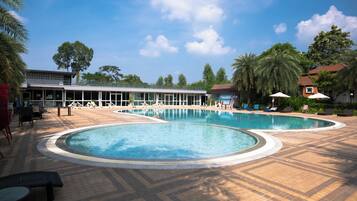 A pool area with two circular pools, lounge chairs, and umbrellas.