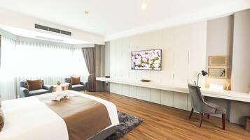 A modern hotel room with a large bed, a desk, and a TV on the wall.