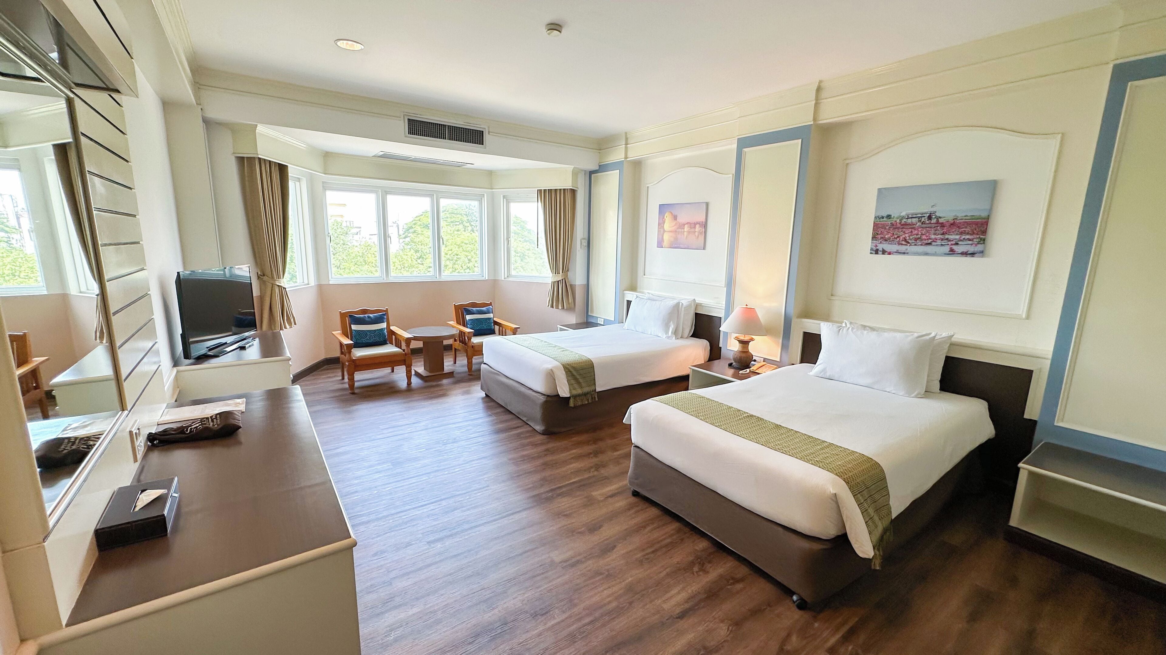 Habitación de hotel con dos camas, un escritorio, una silla, un televisor y una ventana con cortinas.