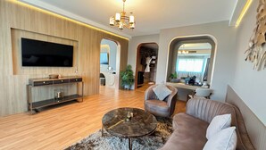 Una sala de estar moderna con un televisor de pantalla plana, paneles de madera, una mesa de centro y un sofá.
