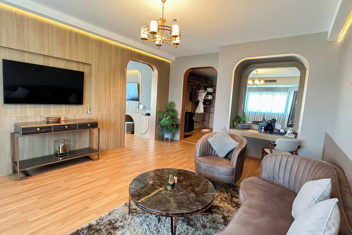 Una sala de estar moderna con un televisor de pantalla plana, paneles de madera, una mesa de centro y un sofá.