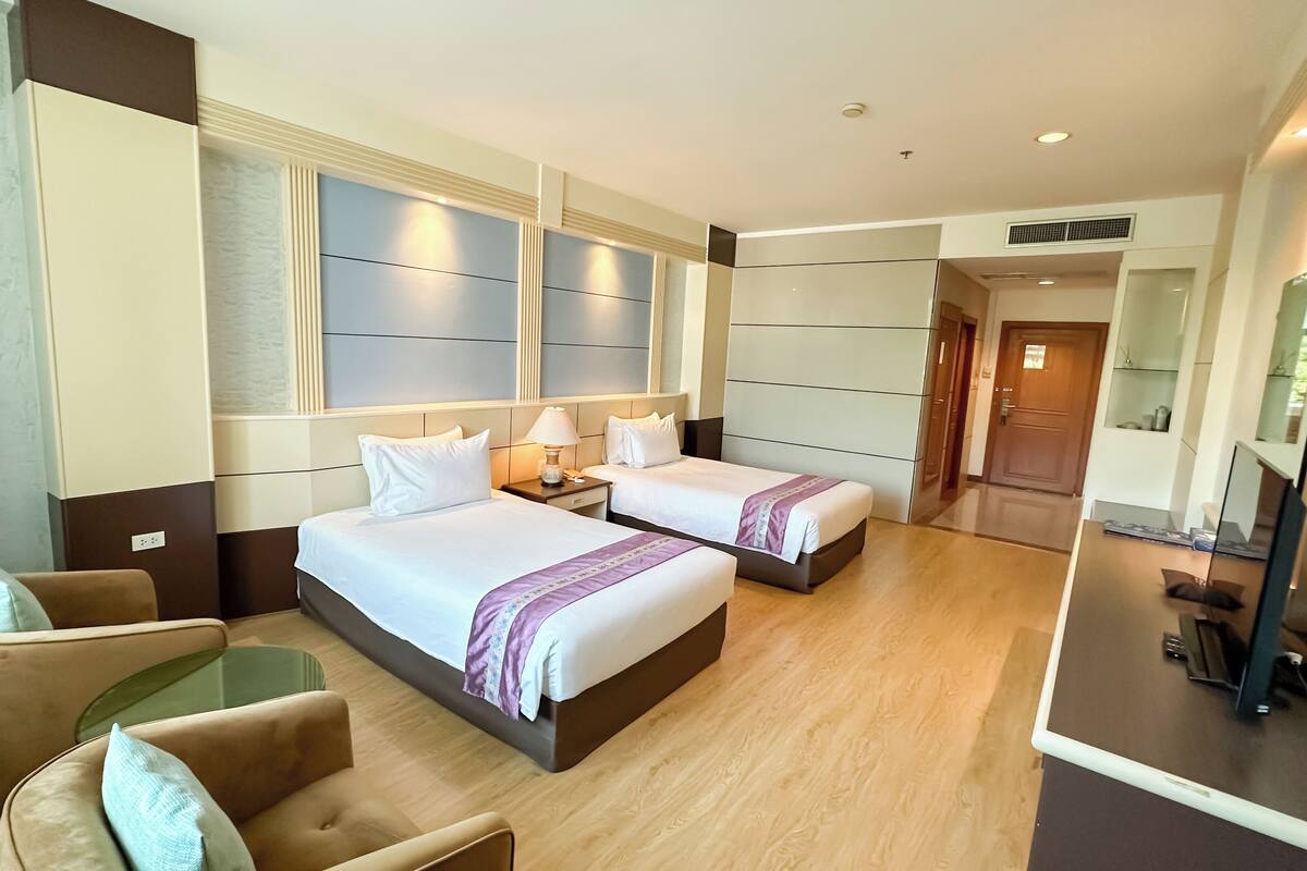 Una habitación de hotel con dos camas, un sofá, una mesita y un espejo.