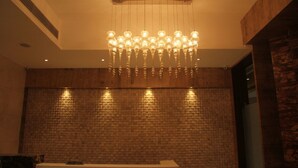 Uma área de recepção com um lustre moderno, um balcão e uma parede de tijolos texturizados.