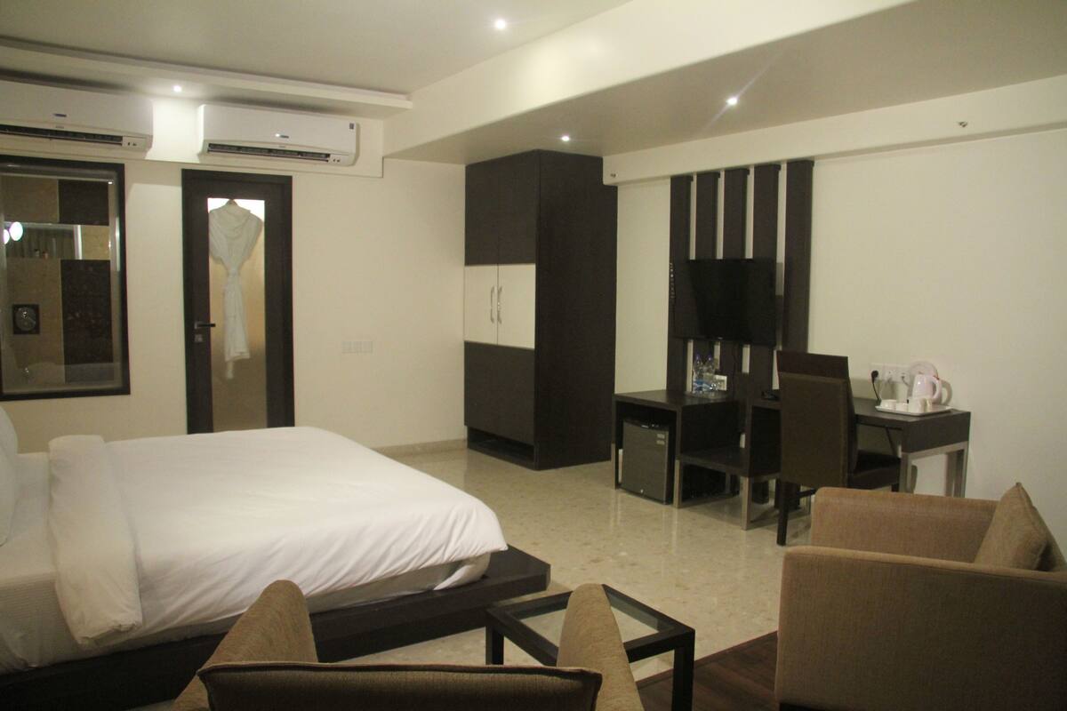 A hotel room with a bed, a desk, a chair, and a television.