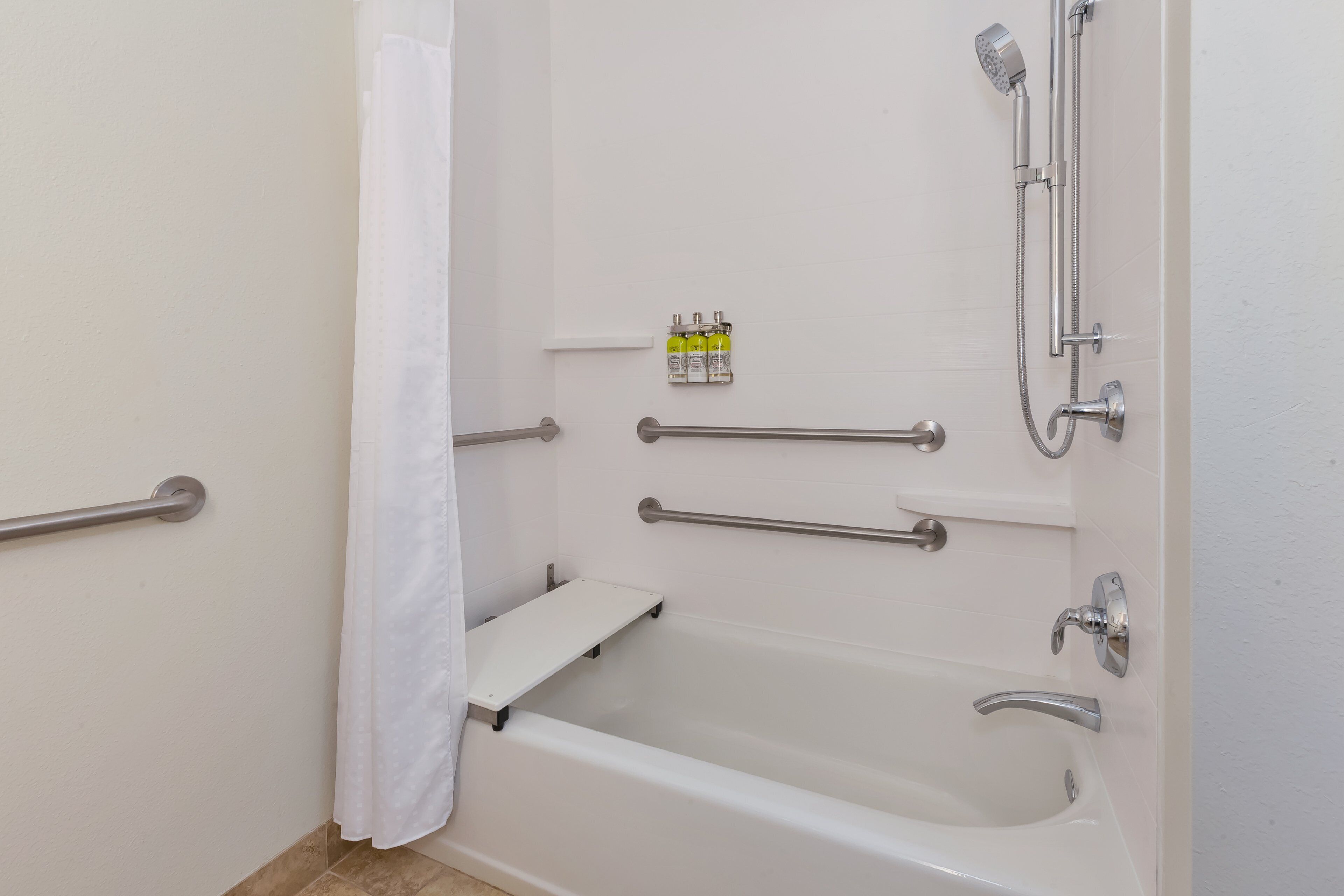 A modern bathroom with a bathtub, shower, and grab bars.