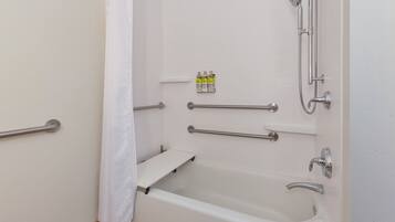 A modern bathroom with a bathtub, shower, and grab bars.