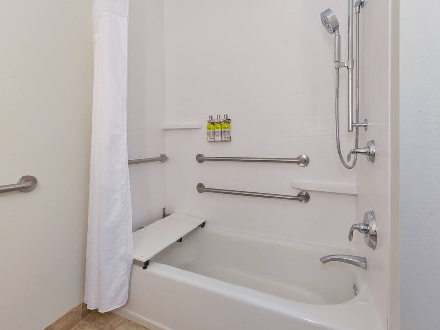 Un baño moderno con bañera, ducha y barras de apoyo.