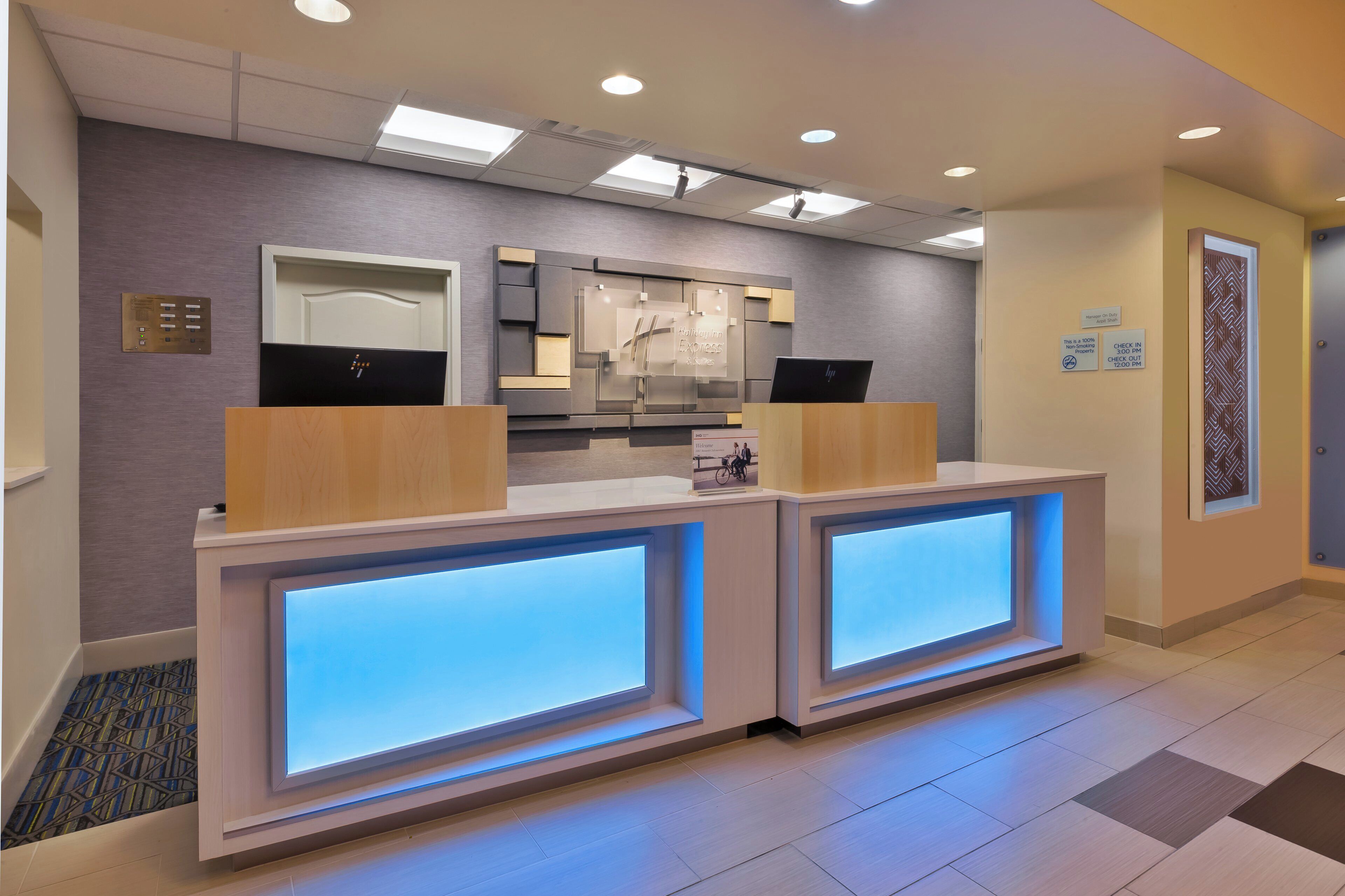 A hotel reception desk with a modern design, featuring a check-in counter and a digital display.
