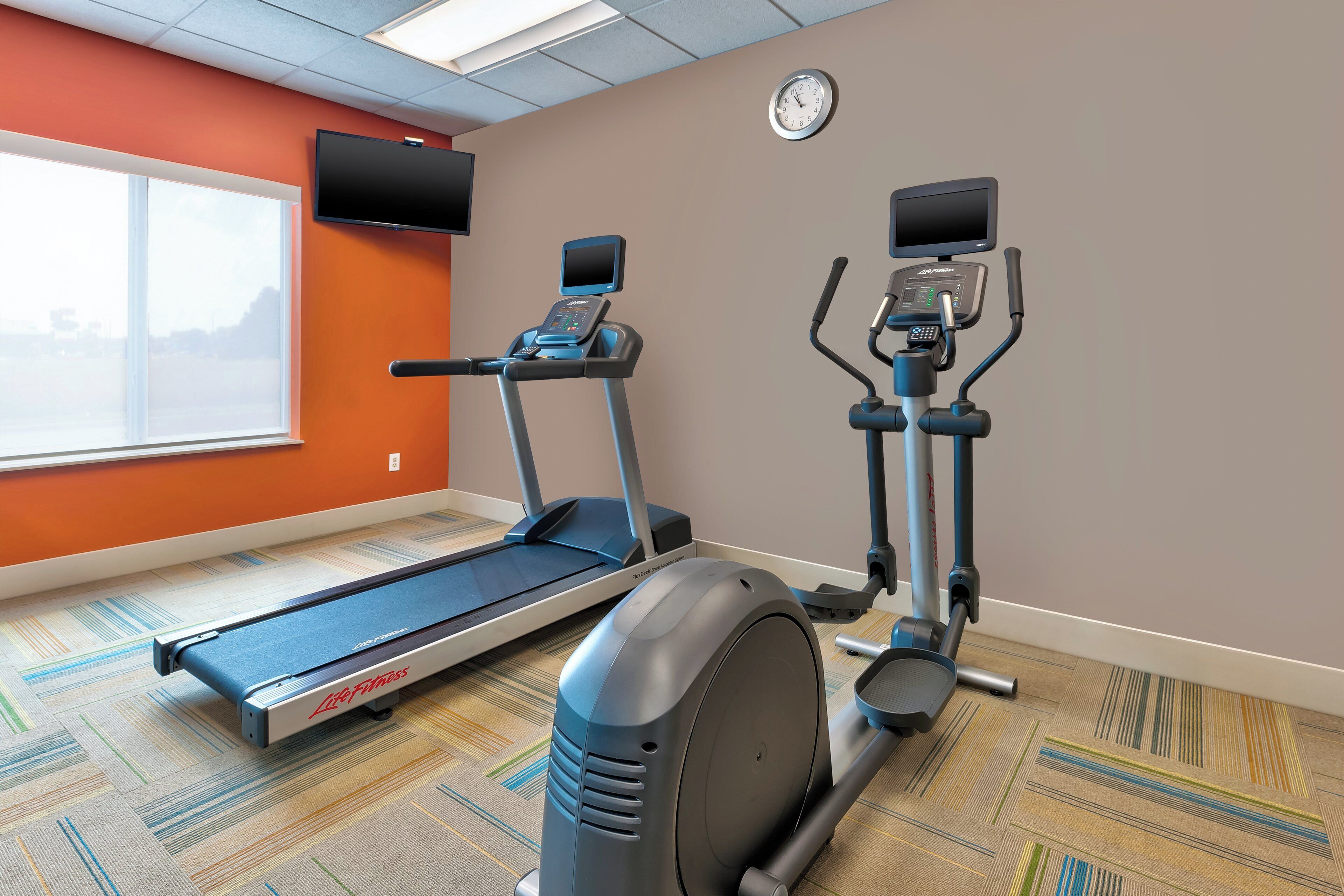 A fitness room with a treadmill, elliptical, and a stationary bike.