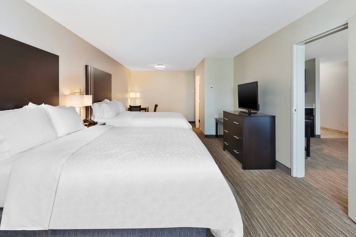 A hotel room with two beds, a desk, a television, and a wardrobe.