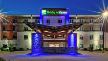 Ein Holiday Inn Express Hotel mit einem modernen Eingang, der eine Steinfassade und blaue Beleuchtung aufweist.