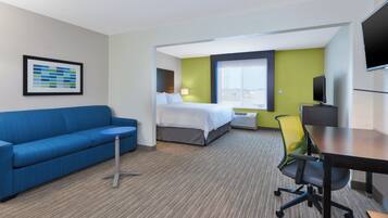 Een hotelkamer met een blauwe bank, een bed, een bureau en een televisie.