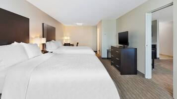 A hotel room with two beds, a desk, a chair, a television, and a wardrobe.