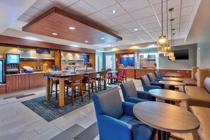 A hotel breakfast area with a counter, seating, and a television. - Holiday Inn Express & Suites Effingham by IHG (Effingham)