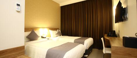 A hotel room with two beds, a desk, a chair, a television, and a curtain.