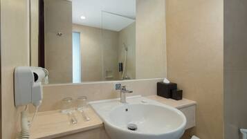 A modern bathroom with a large sink, a hairdryer, and a mirror.