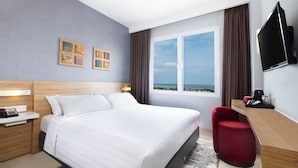 Habitación de hotel con cama, escritorio, televisor y ventana con vistas.