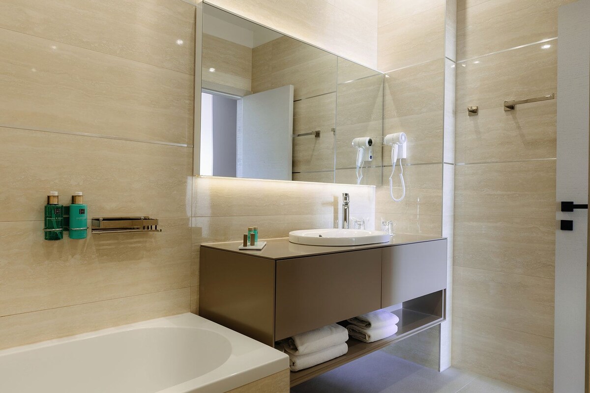 A modern bathroom with a bathtub, a vanity with a mirror, and a shower area.