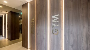 A modern hotel lobby with wooden paneling and illuminated signage.