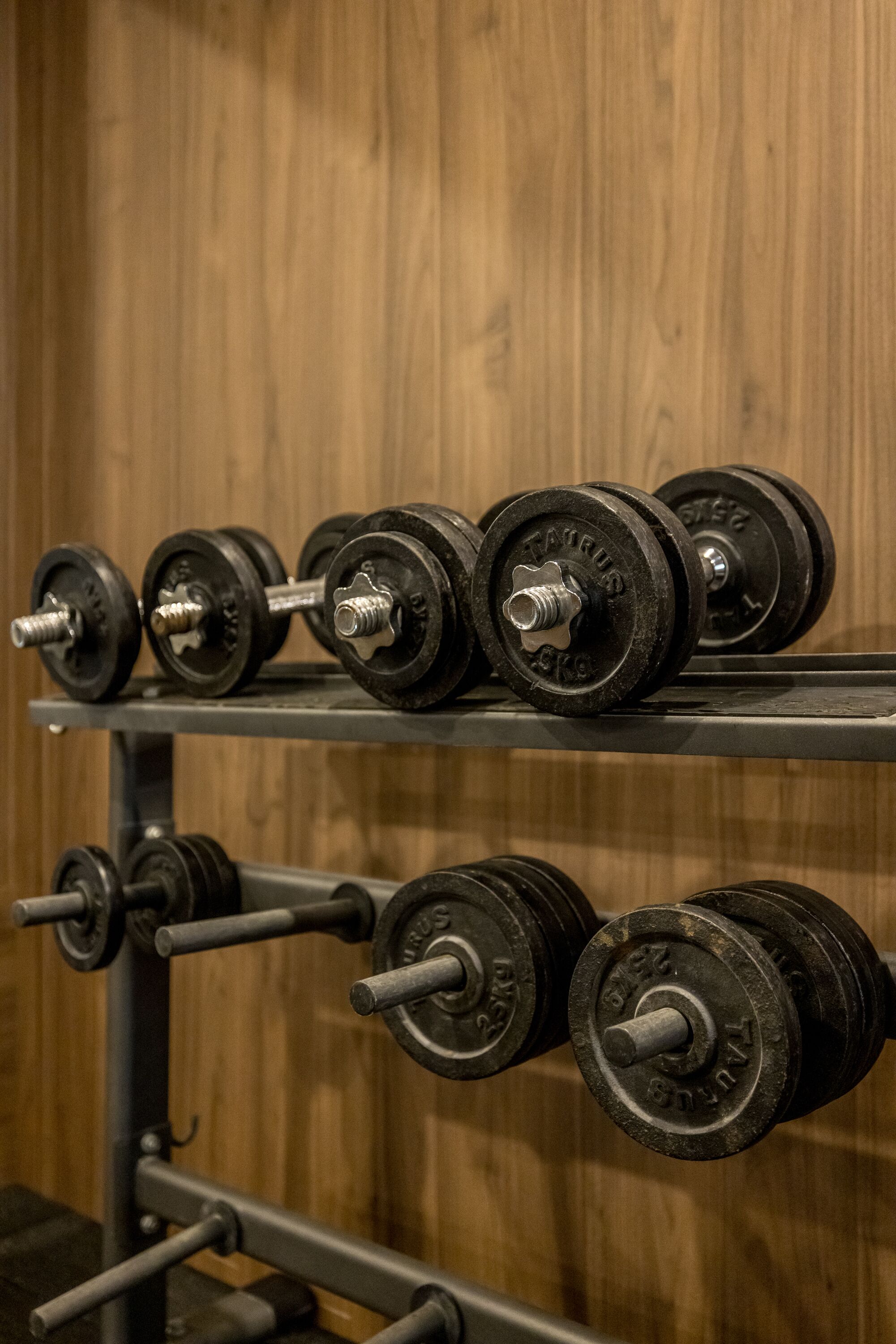 A rack of dumbbells with weight markings, set against a wooden background.
