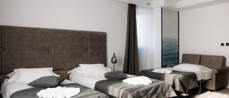 Ett hotellrum med två sängar, en stor spegel och utsikt över havet.