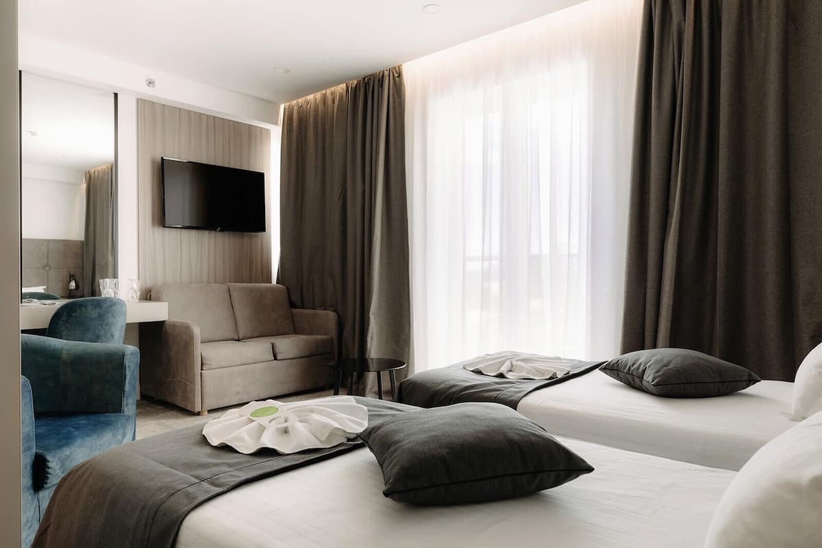 Ein Hotelzimmer mit zwei Betten, einem Schlafsofa, einem Fernseher und einem Schreibtisch.