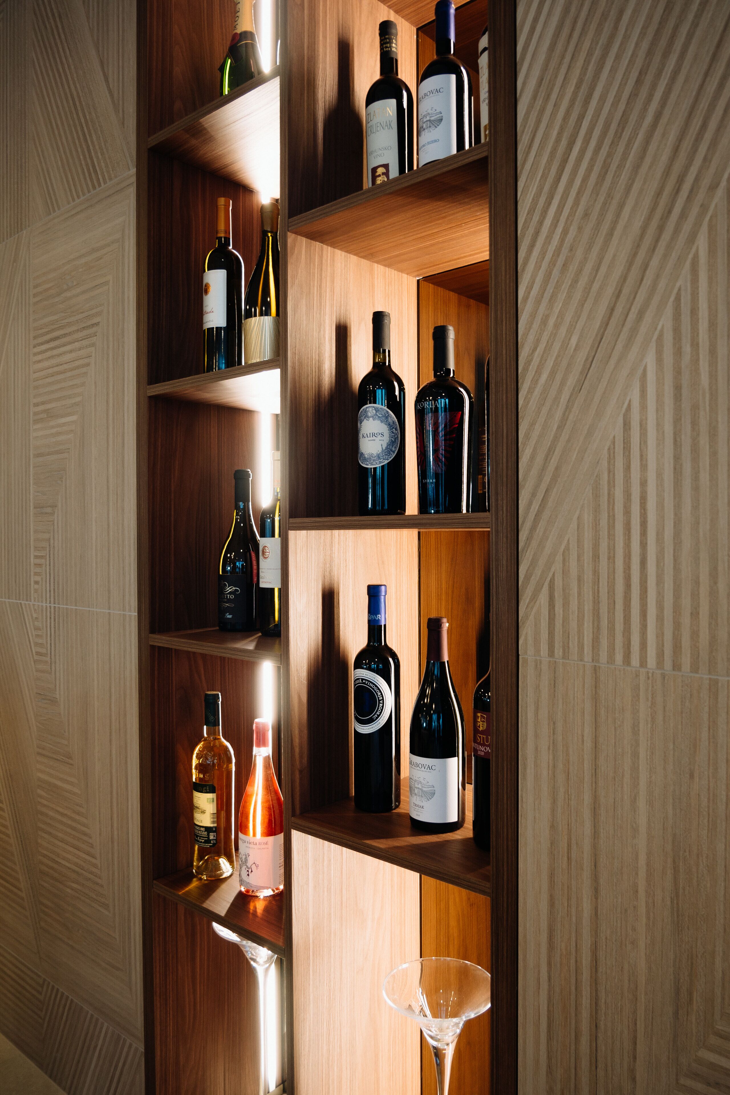 A wooden wine rack with various bottles and a martini glass.