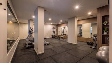Ett modernt gym med träningsutrustning, speglar och ett rent, kaklat golv.