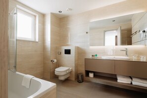A modern bathroom with a glass shower enclosure, a toilet, a sink with a mirror, and a vanity with towels.