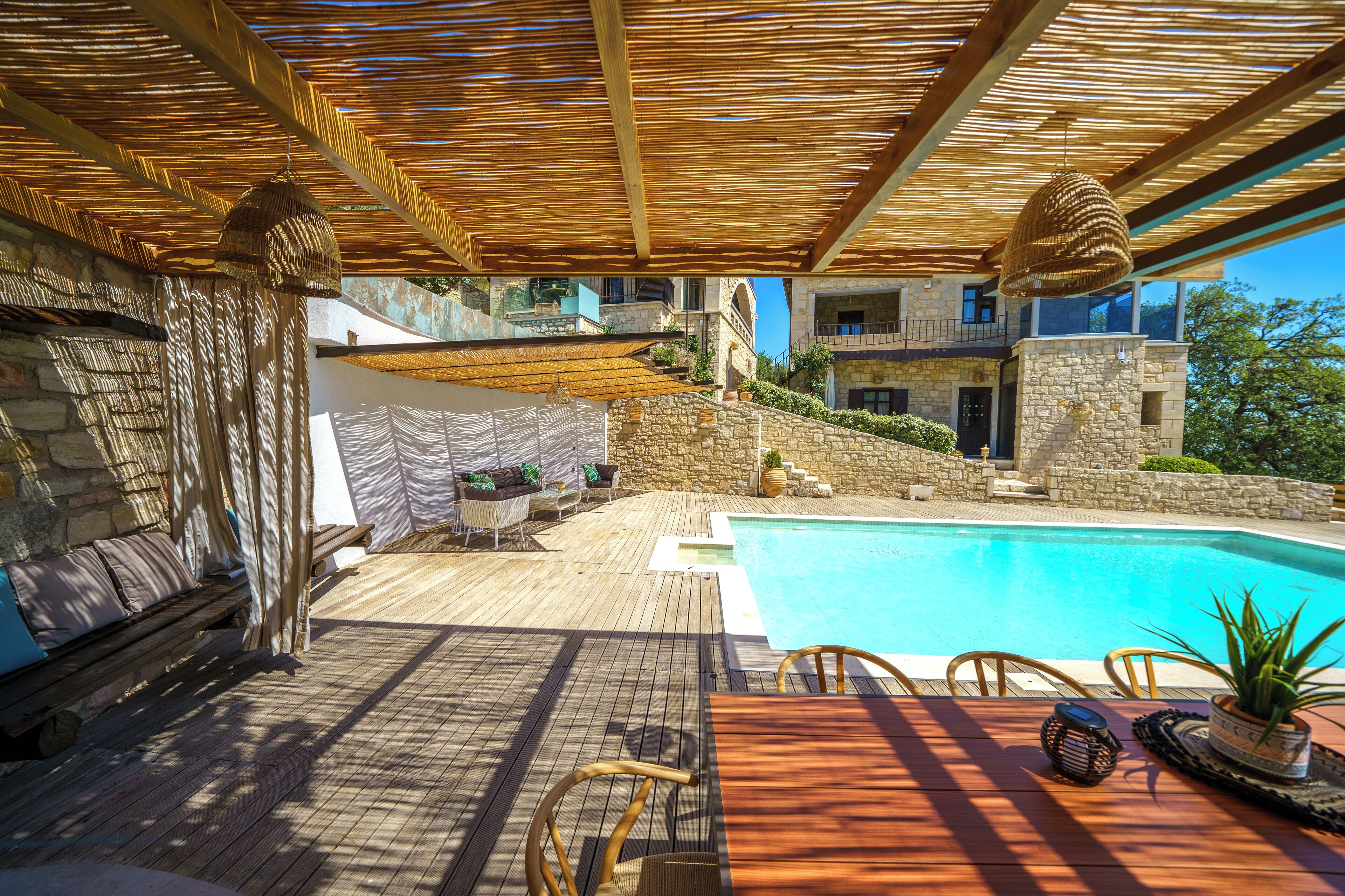 A wooden deck with a pool, outdoor furniture, and a stone wall.