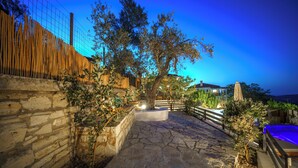 A stone pathway leading to a pool area with a wooden fence and a tree. - Asion Lithos (Heraklion)