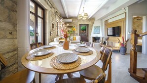 A dining area with a round table set for six, surrounded by wooden chairs. - Asion Lithos (Heraklion)