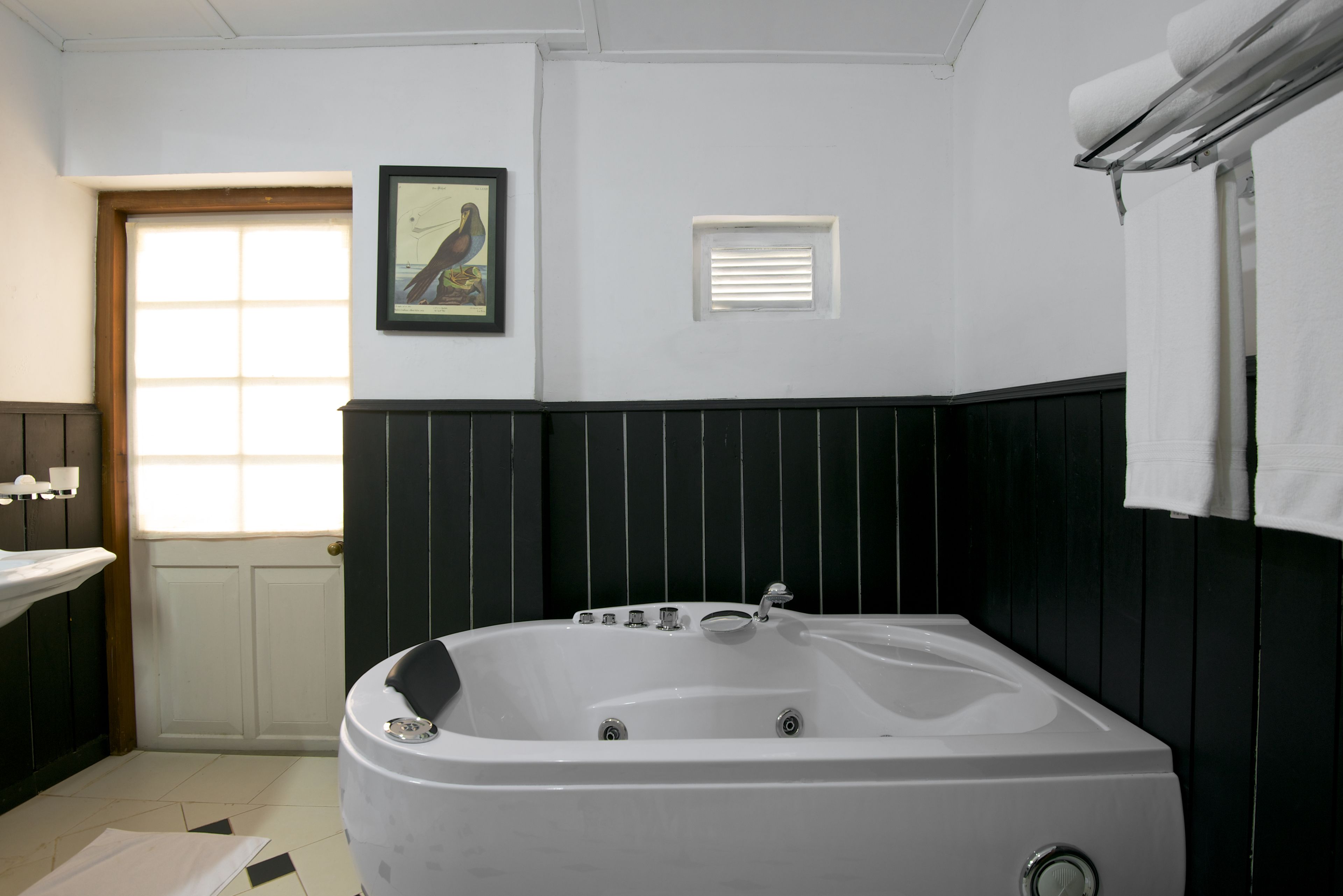 A modern bathroom with a freestanding bathtub, a sink, and a framed picture on the wall.