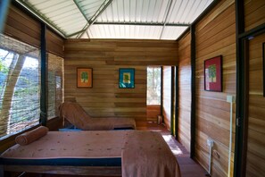 A wooden cabin with two beds, wooden walls, and framed pictures.