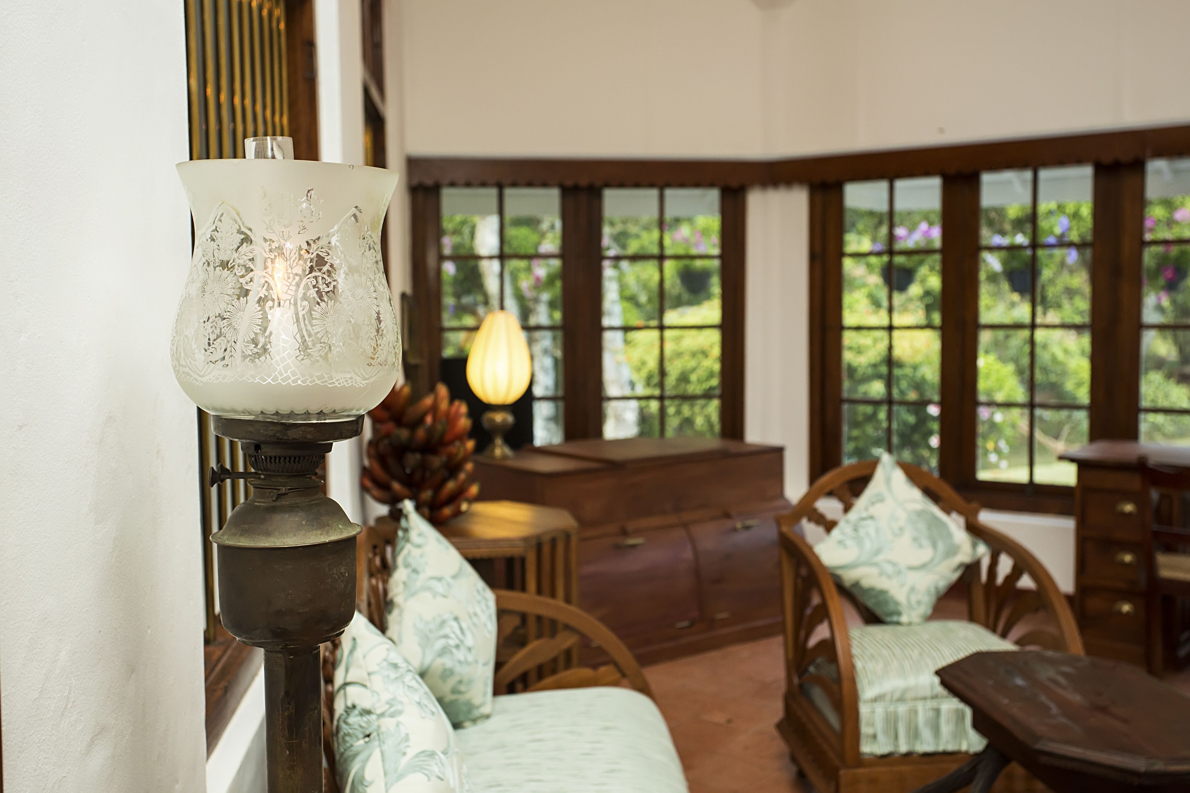 A room with a large window, a wooden chair, a table, and a decorative lamp.