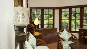 A room with a large window, a wooden chair, a table, and a decorative lamp.