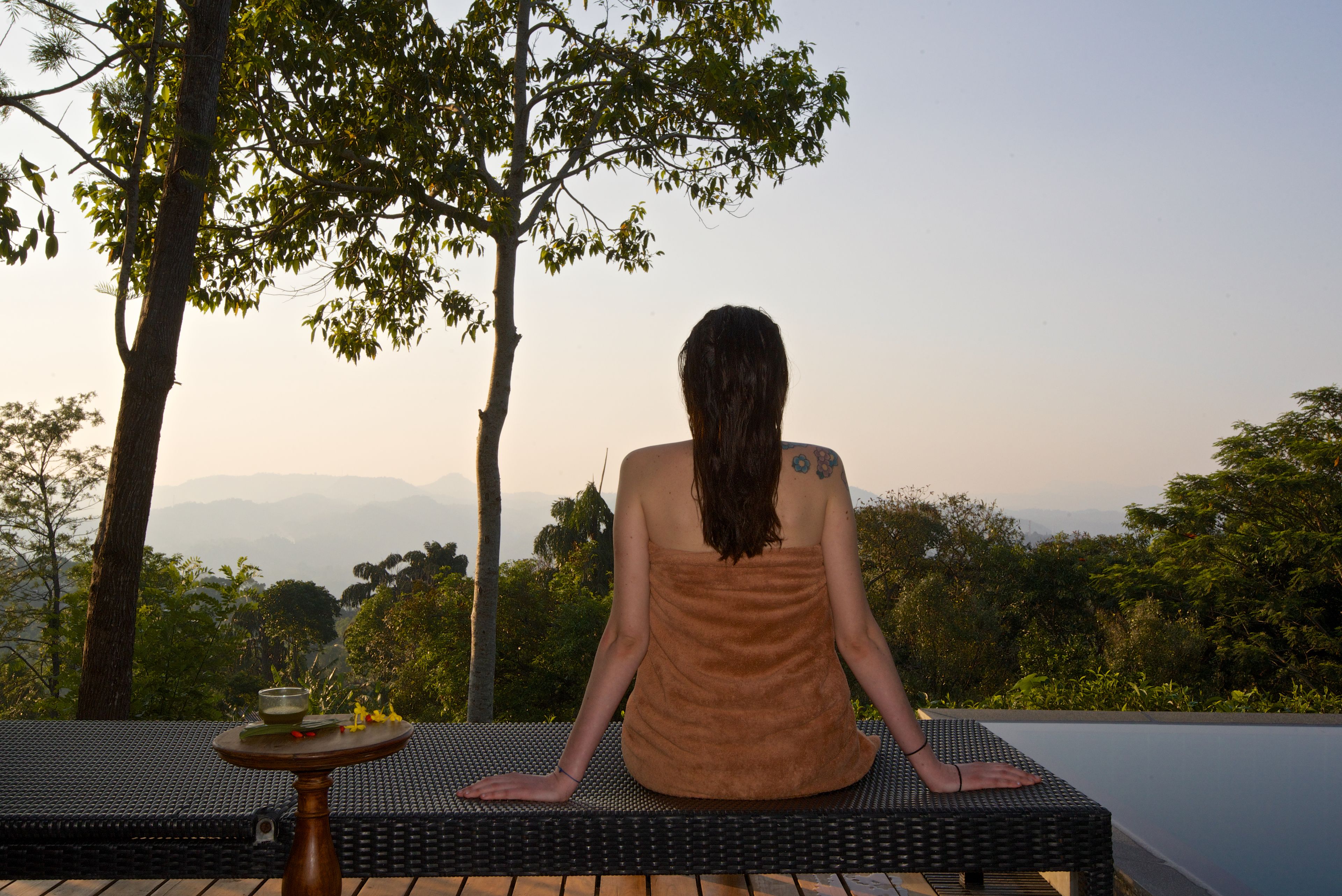 A person sitting on a lounge chair with a view of a mountainous landscape.