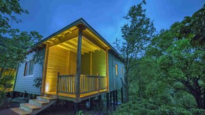 A wooden house with a balcony, elevated on stilts, surrounded by dense greenery. - Mountbatten Bungalow (Kandy)