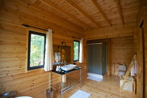 A wooden cabin bathroom with a sink, mirror, and shower.