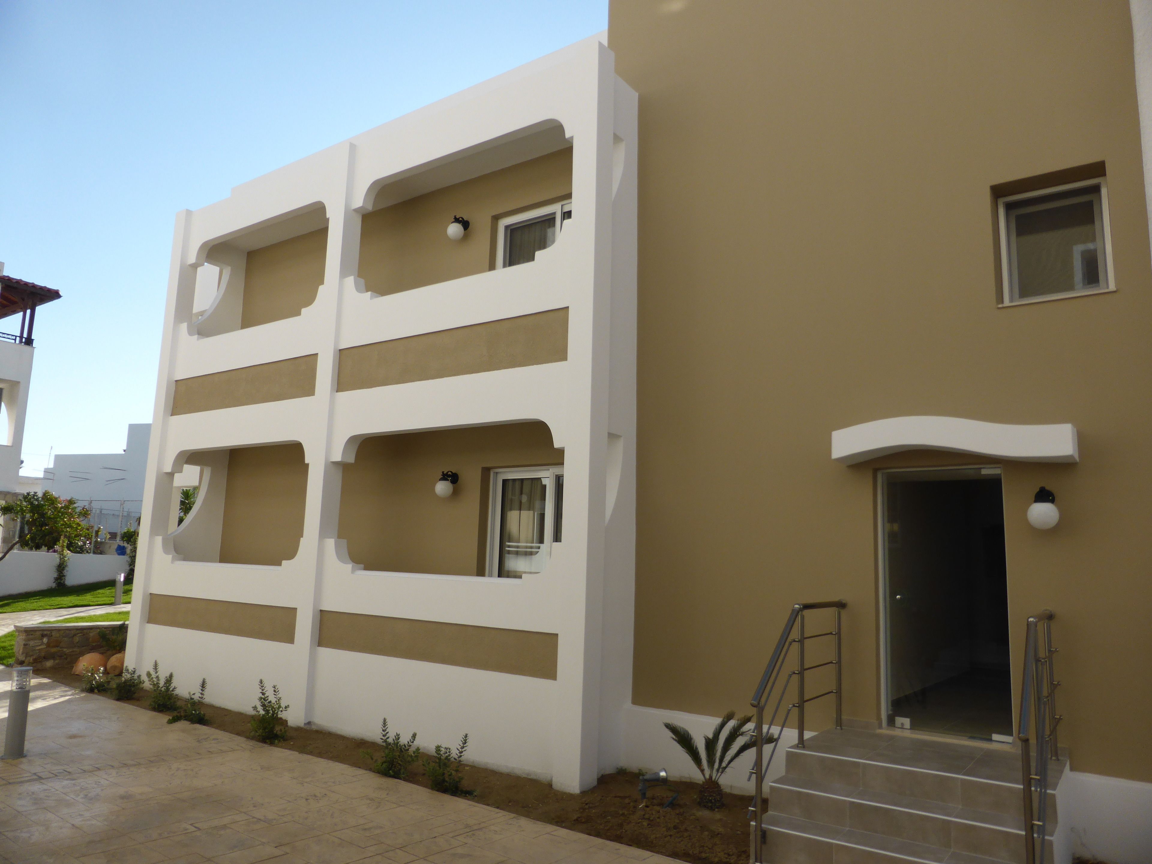 Un edificio moderno con facciata color beige, diversi balconi e una scala che conduce all'ingresso.